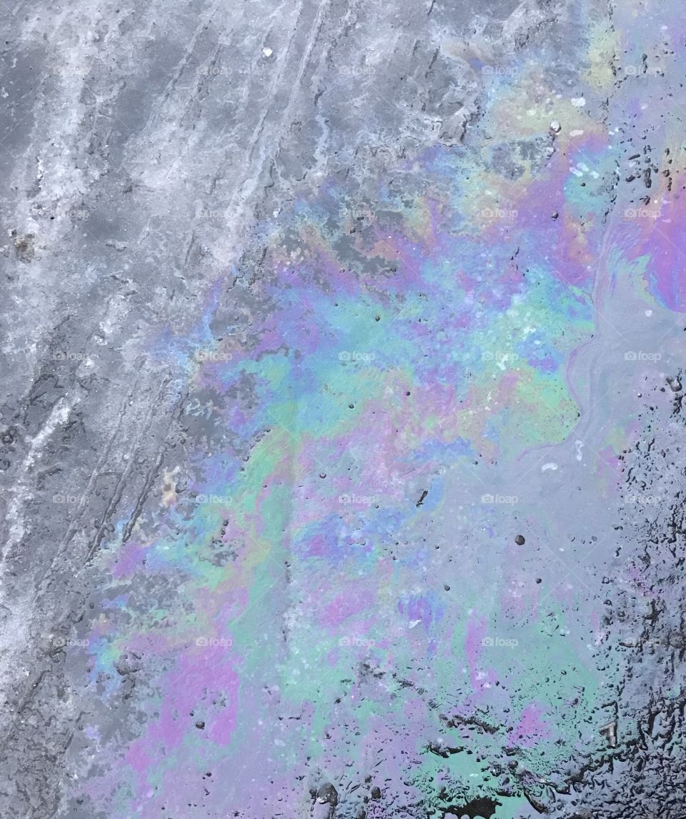 Nifty shot of ice, oil, and rain water make a pastel rainbow on black pavement in winter. 