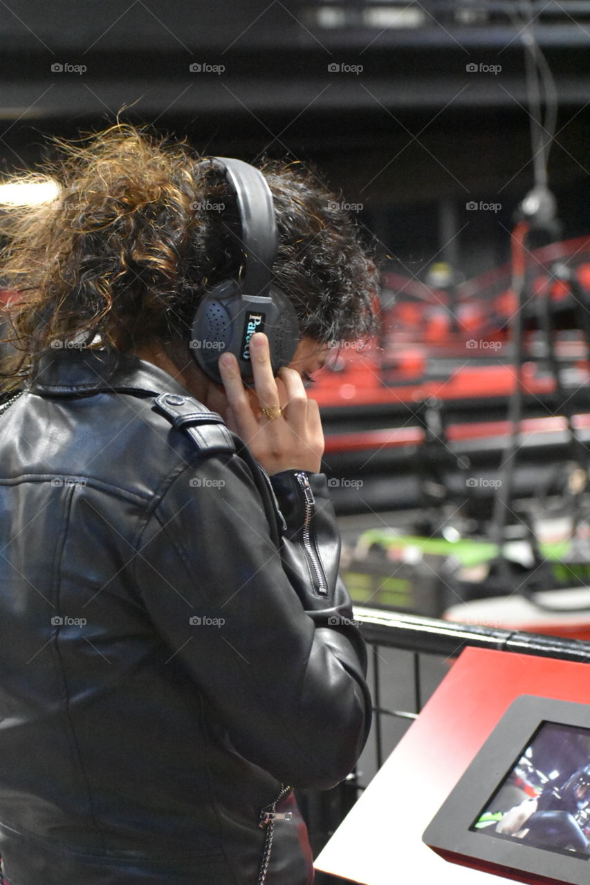 woman wearing head phones listening to video. black leather jacket. brunette.