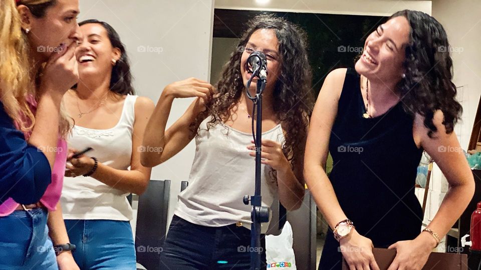 Group of women singing an emotional song, while laughing and enjoying the karaoke.