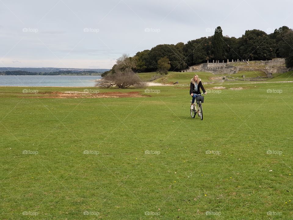 beautyfull girl riding a bike over a green field.