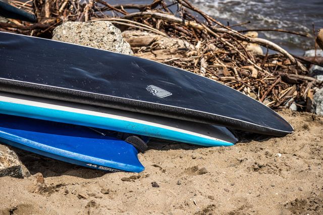 Two surfboards and a boogie board resting on the beach on a warm summer afternoon 