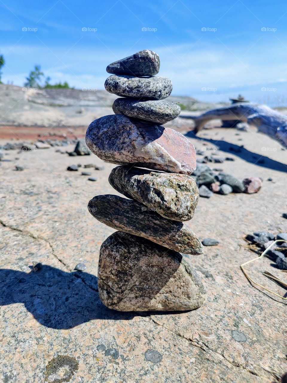 Cairn pyramid from the smooth and oval shore stones on the rock cosat