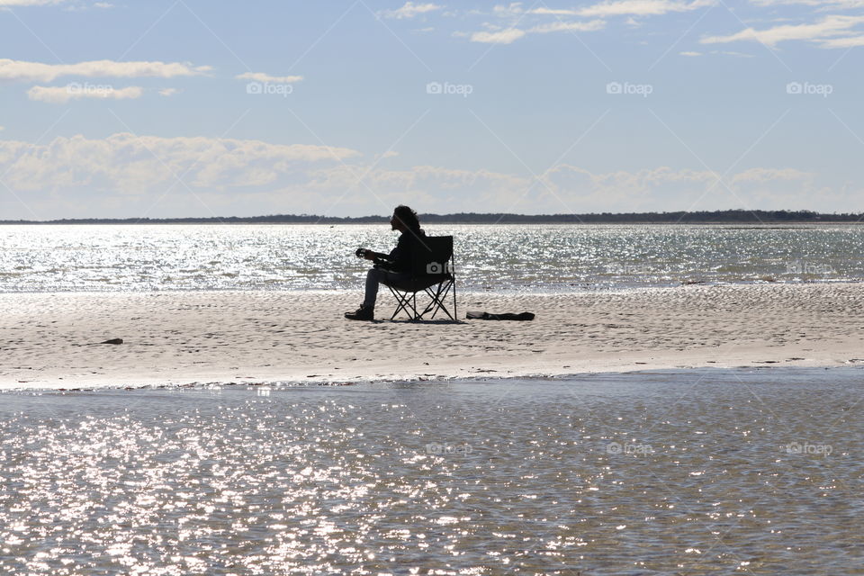 Singing in the wind, surrounded by ocean, lone musician silhouette 