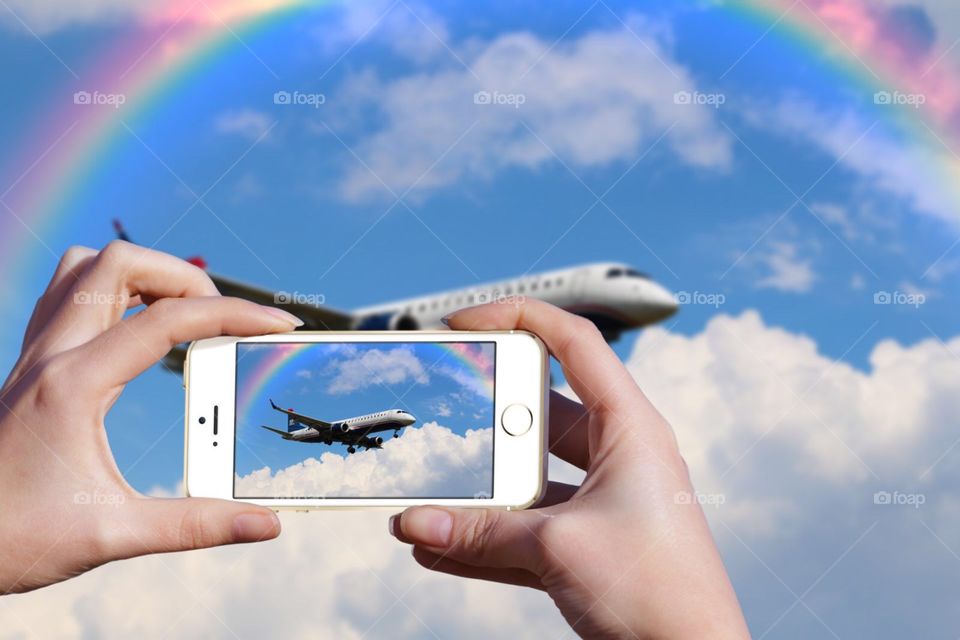 Using my mobile device to take a picture of an airplane landing with a rainbow over it