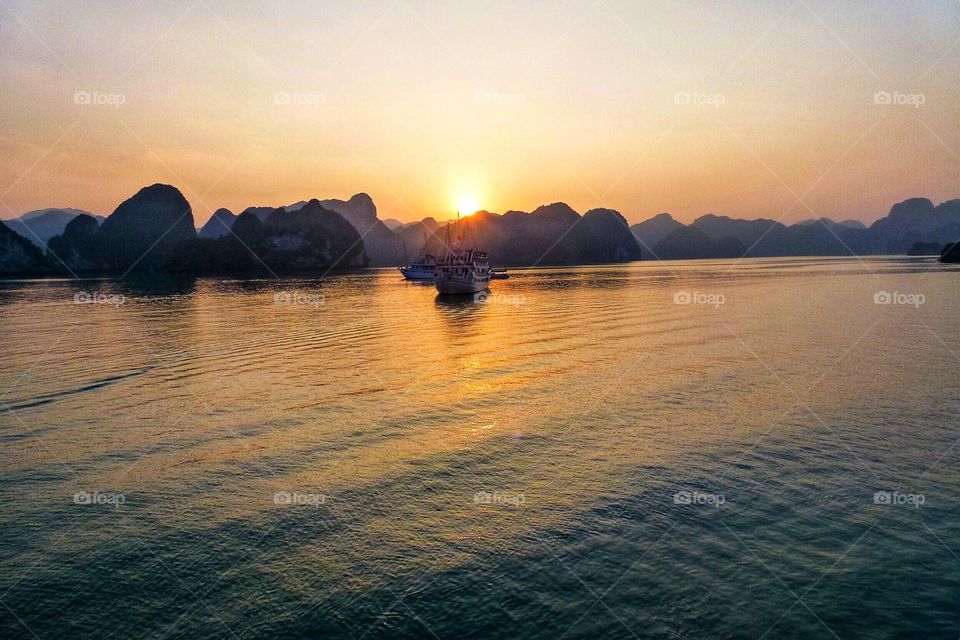 Ships on bay at sunset , natural wonders of the world , the sun falls behind the undulating mountains