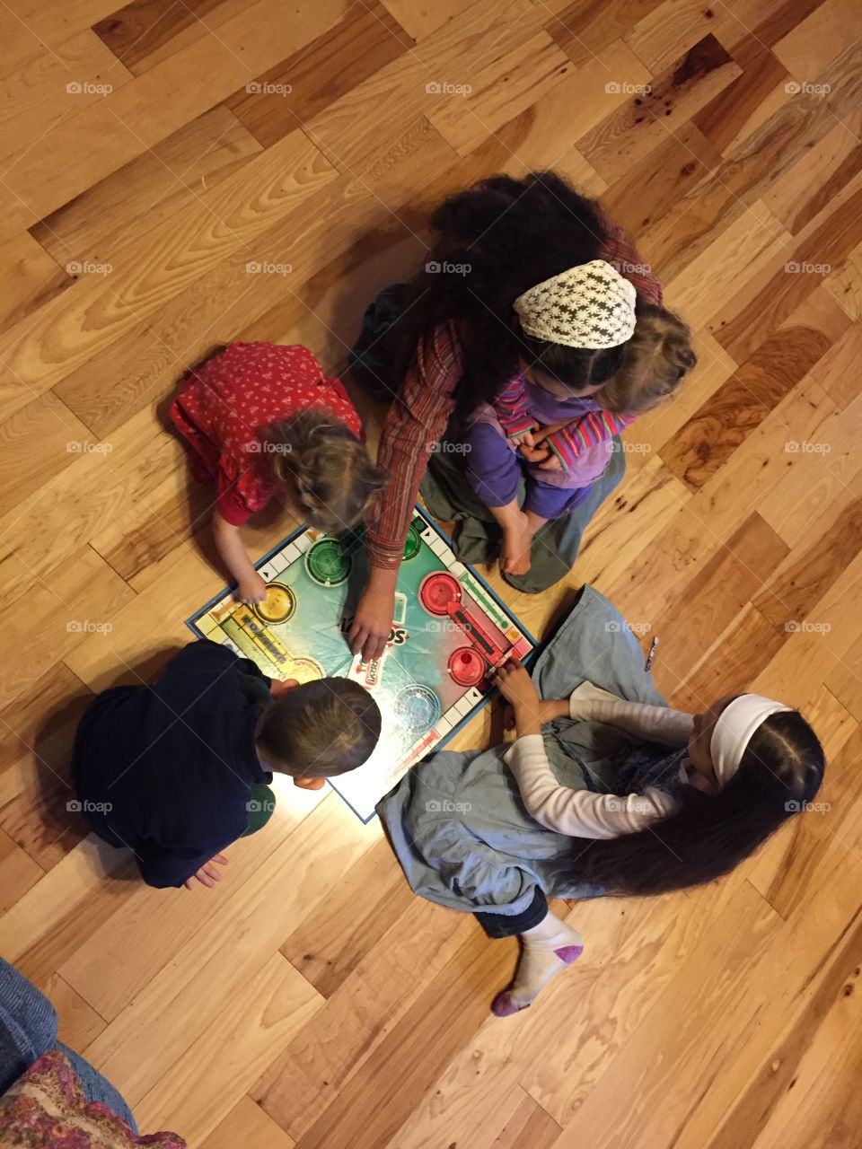 This is a picture taken of some children playing a game on the floor in the house.