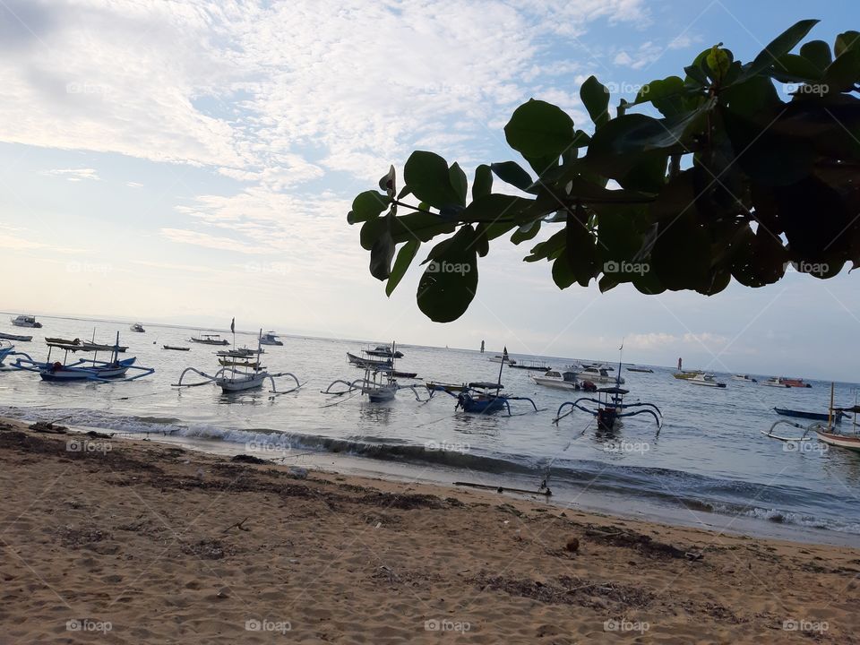 A late sunrise which is seen from the beach that is full of fishing ships