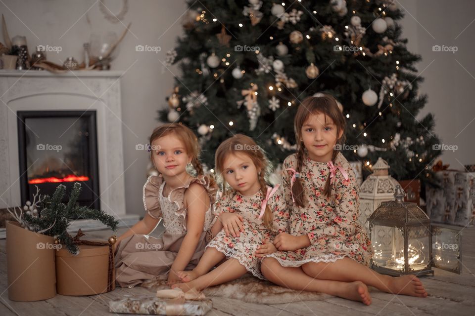 Little sisters near Christmas tree at home