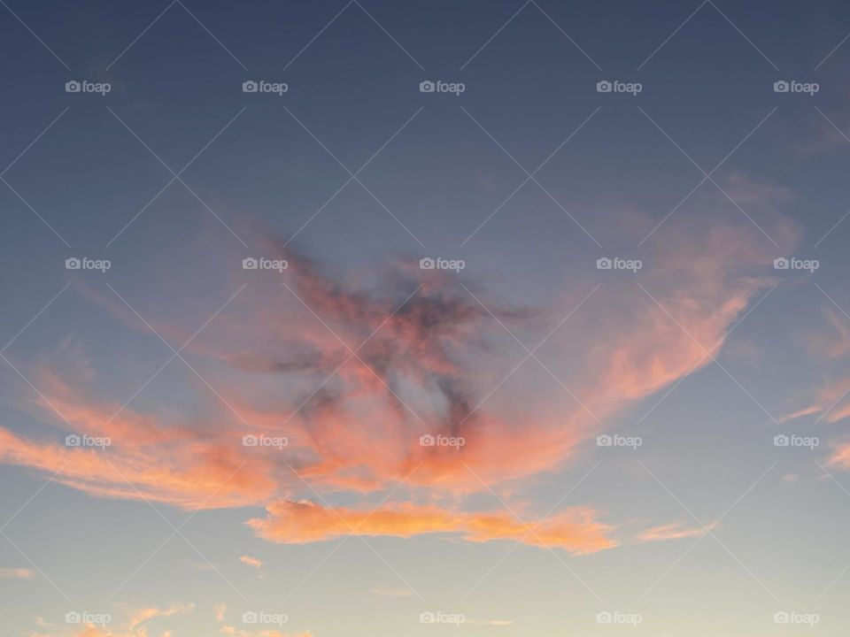Orange and pink clouds across the blue sky.