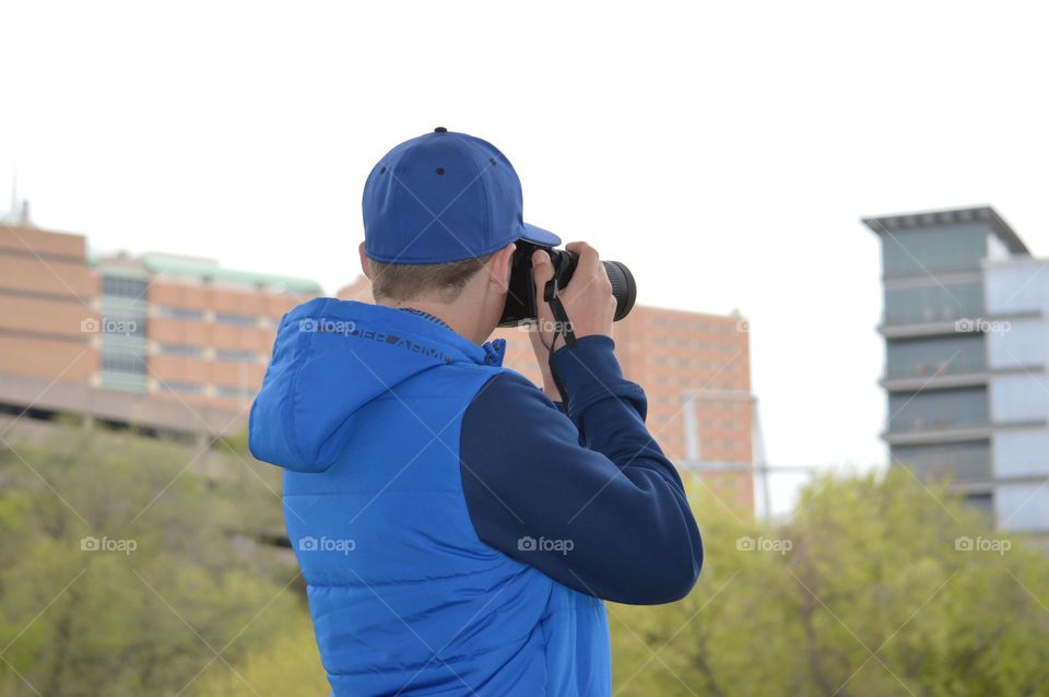 Rear view of man photographing city building