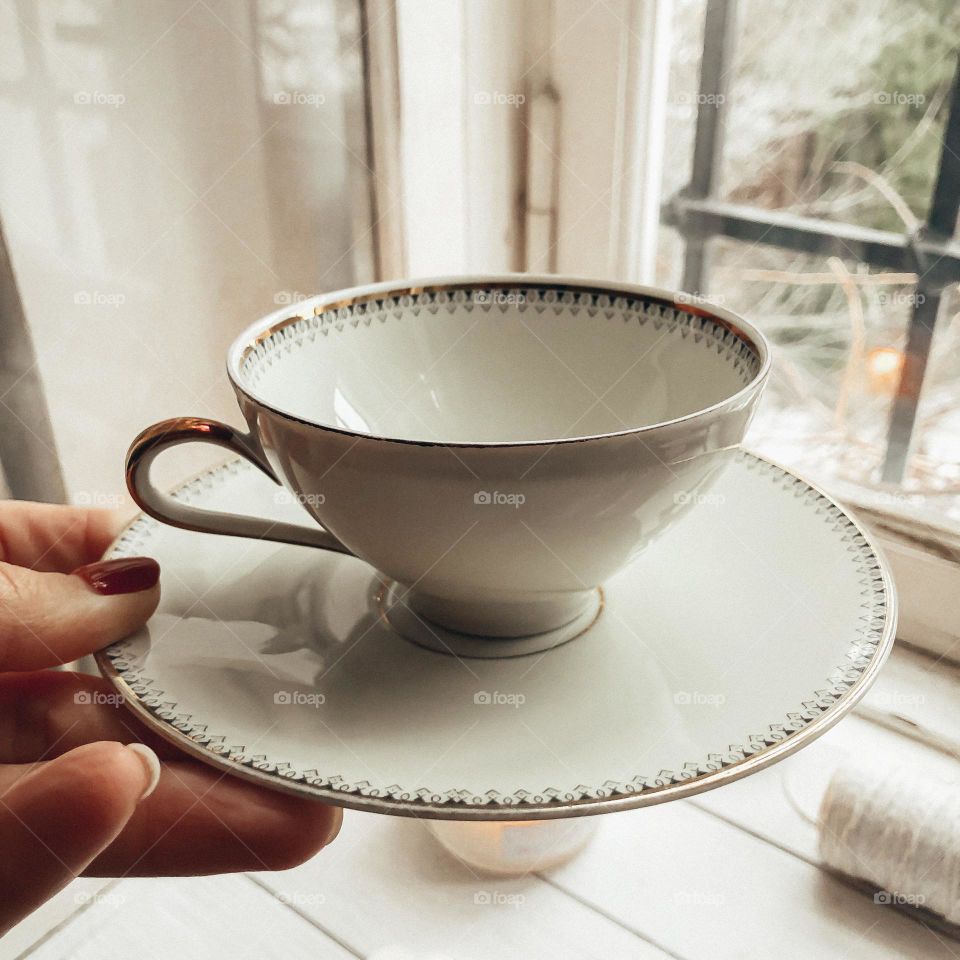 Vintage beige porcelain cup with saucer in hand