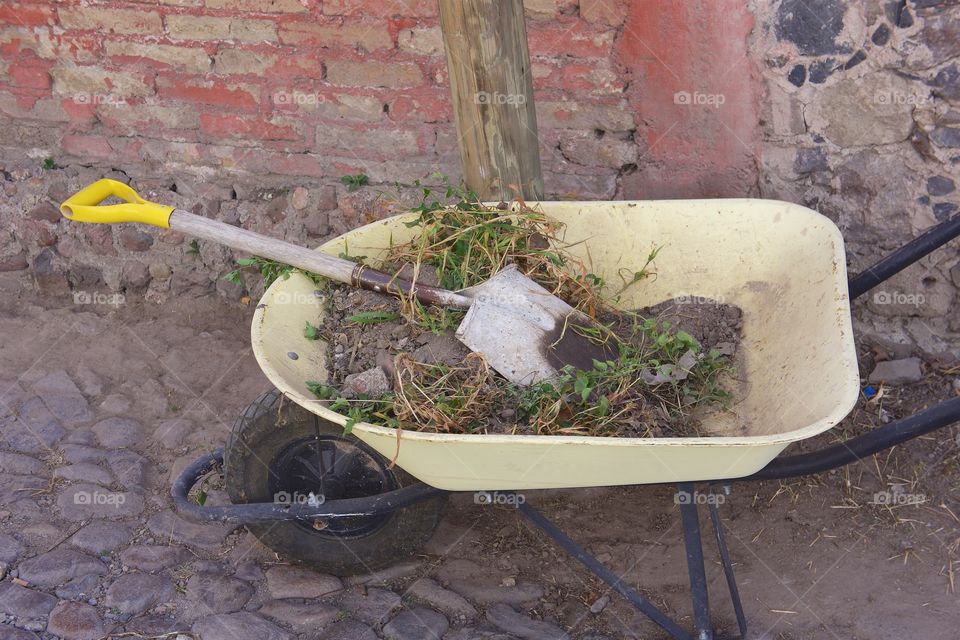 A full wheelbarrow left in front of a house in San Miguel de Allende, Mexico with gardening tools.