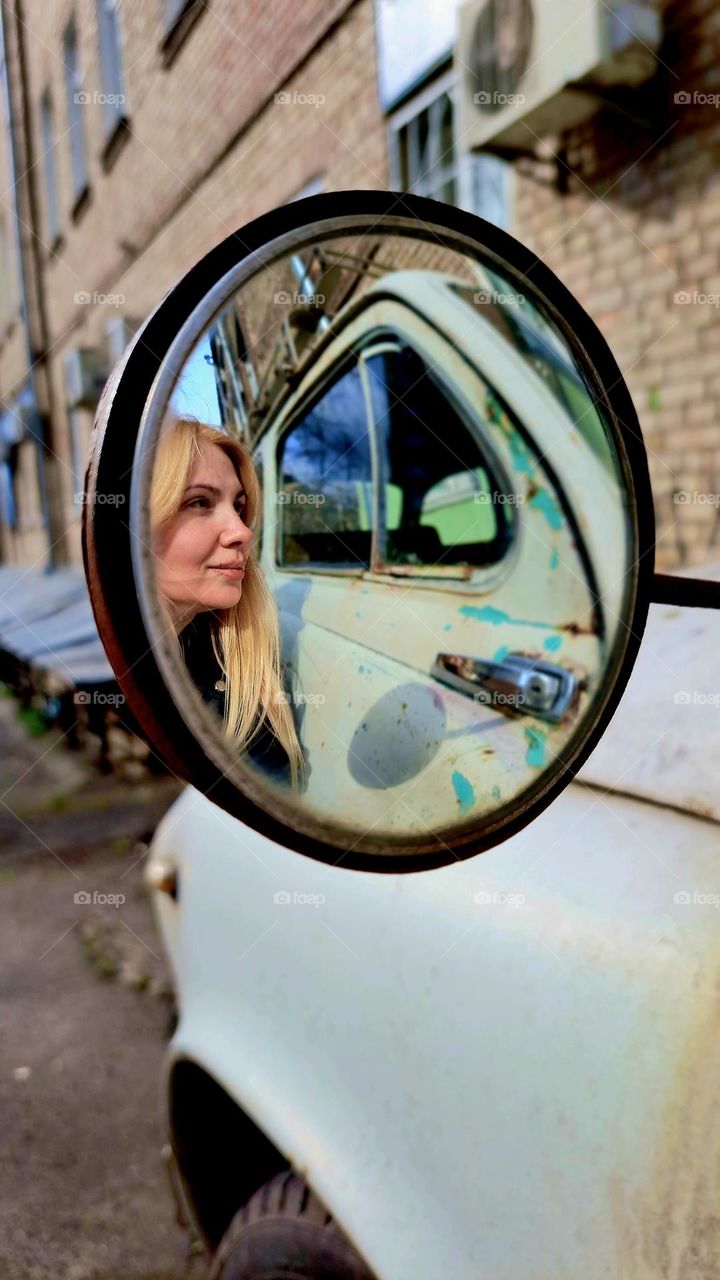 girl looking in the mirror of a car