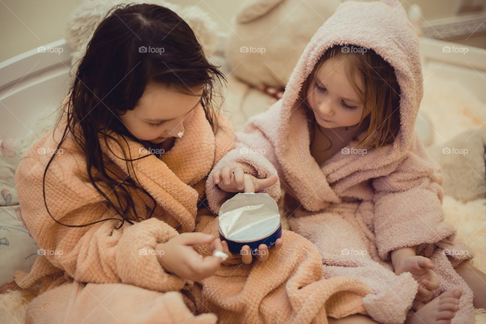 Little sisters in bathrobe with cream