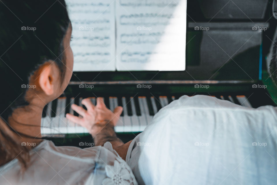 Girl teaches a pupil to play the piano