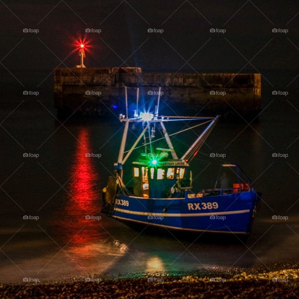 A boat from the Hastings fishing fleet, heads out to sea from the old harbour arm to fish overnight