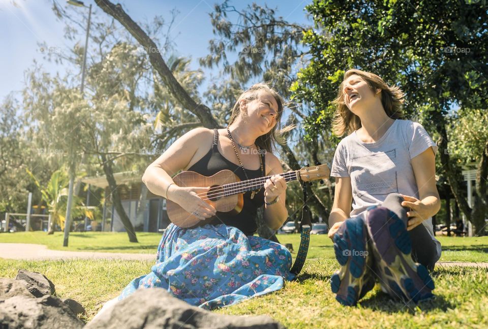 Two women friends singing together in the park