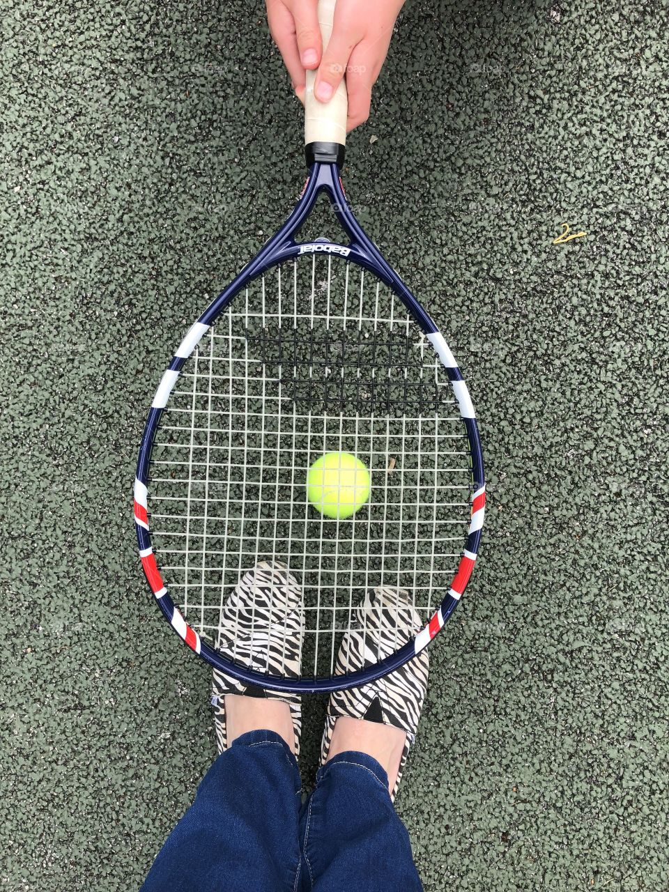 Feet under a tennis racket and ball 