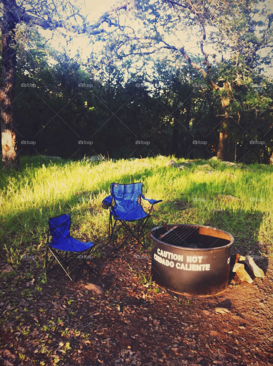A small and large folding chair by a fire pit.