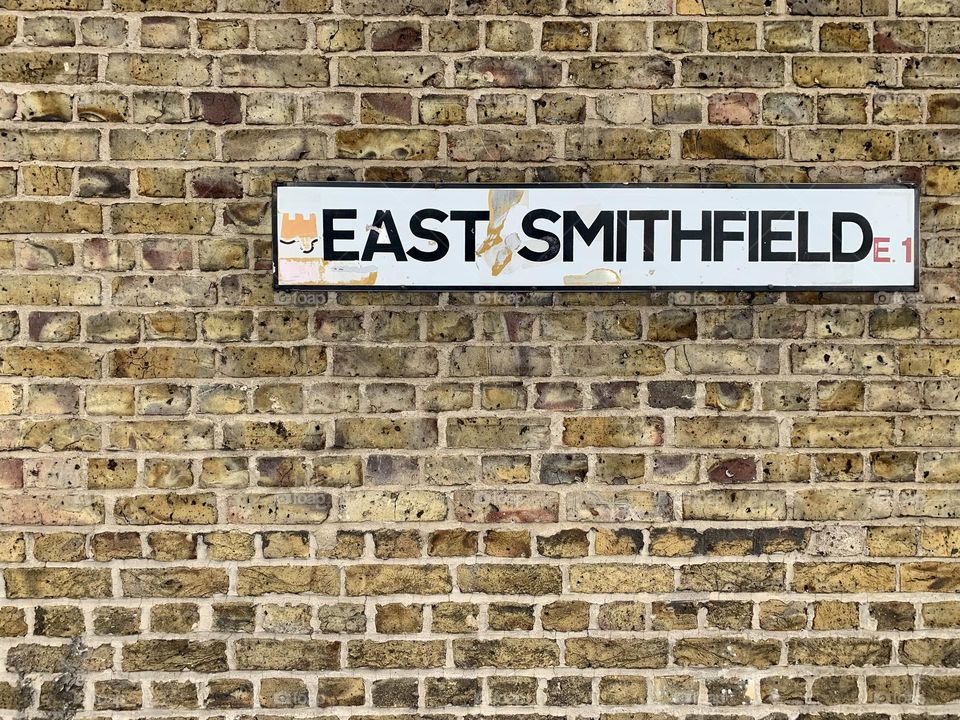 Brick walls in London and East Smithfield white street sign affixed 