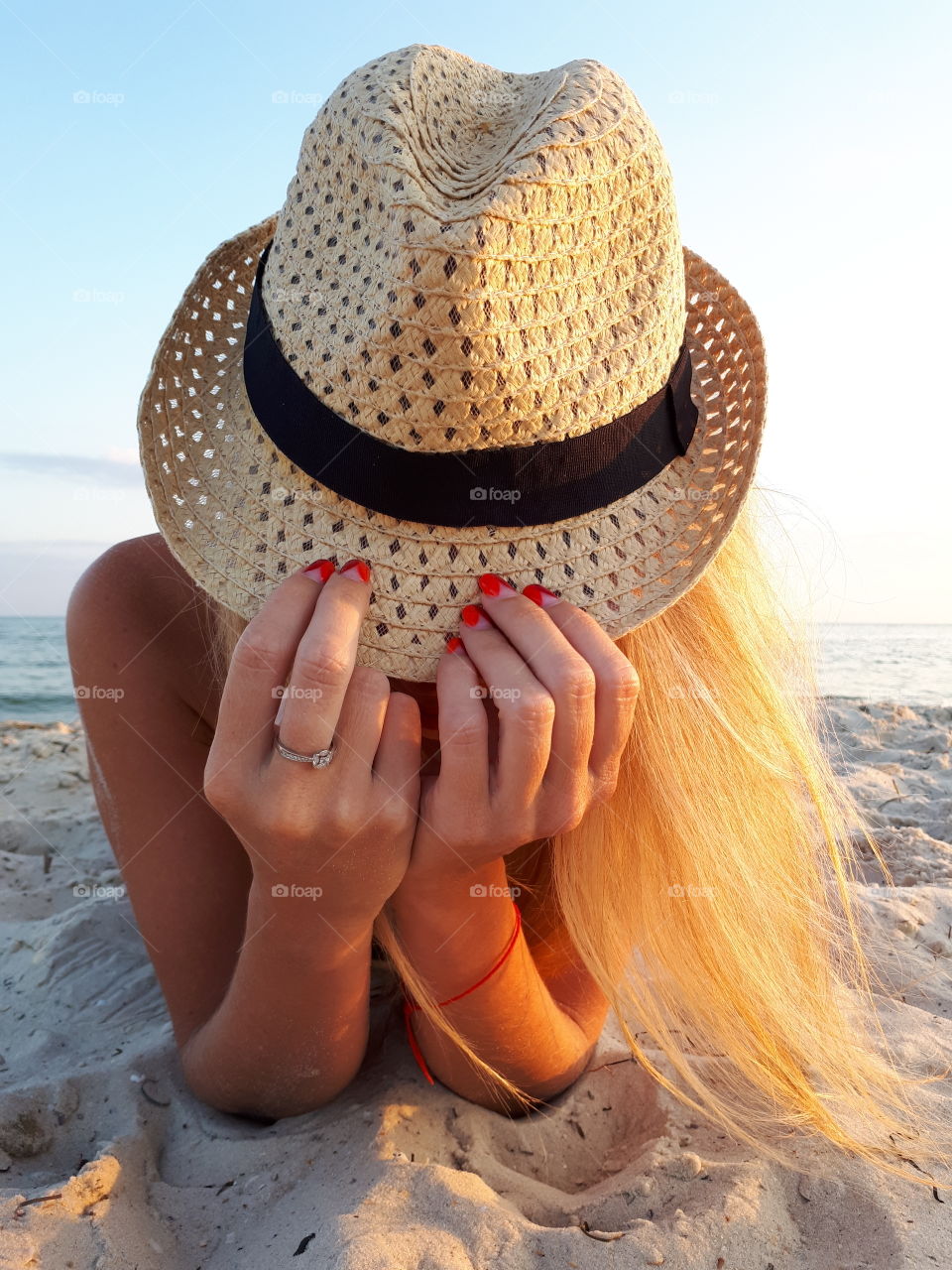 Blond with hat lying on the sand