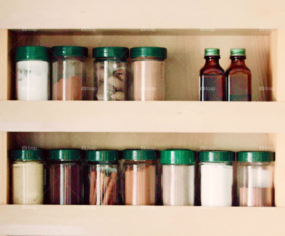 Green Color Story - Spices and flavorings with green lids in a cupboard door spice rack