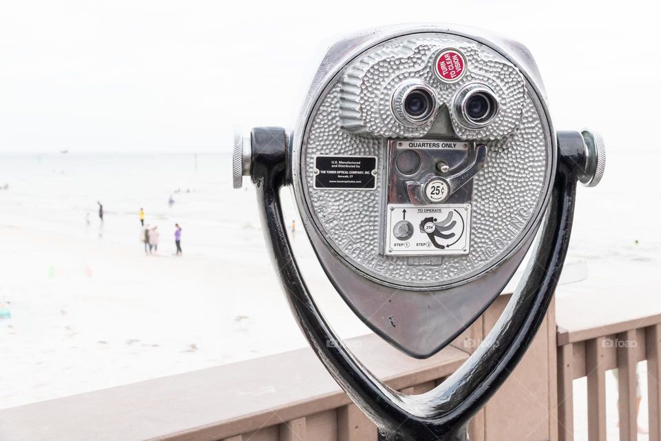 Tourist binoculars on wooden pier with a view of the beach and ocean 