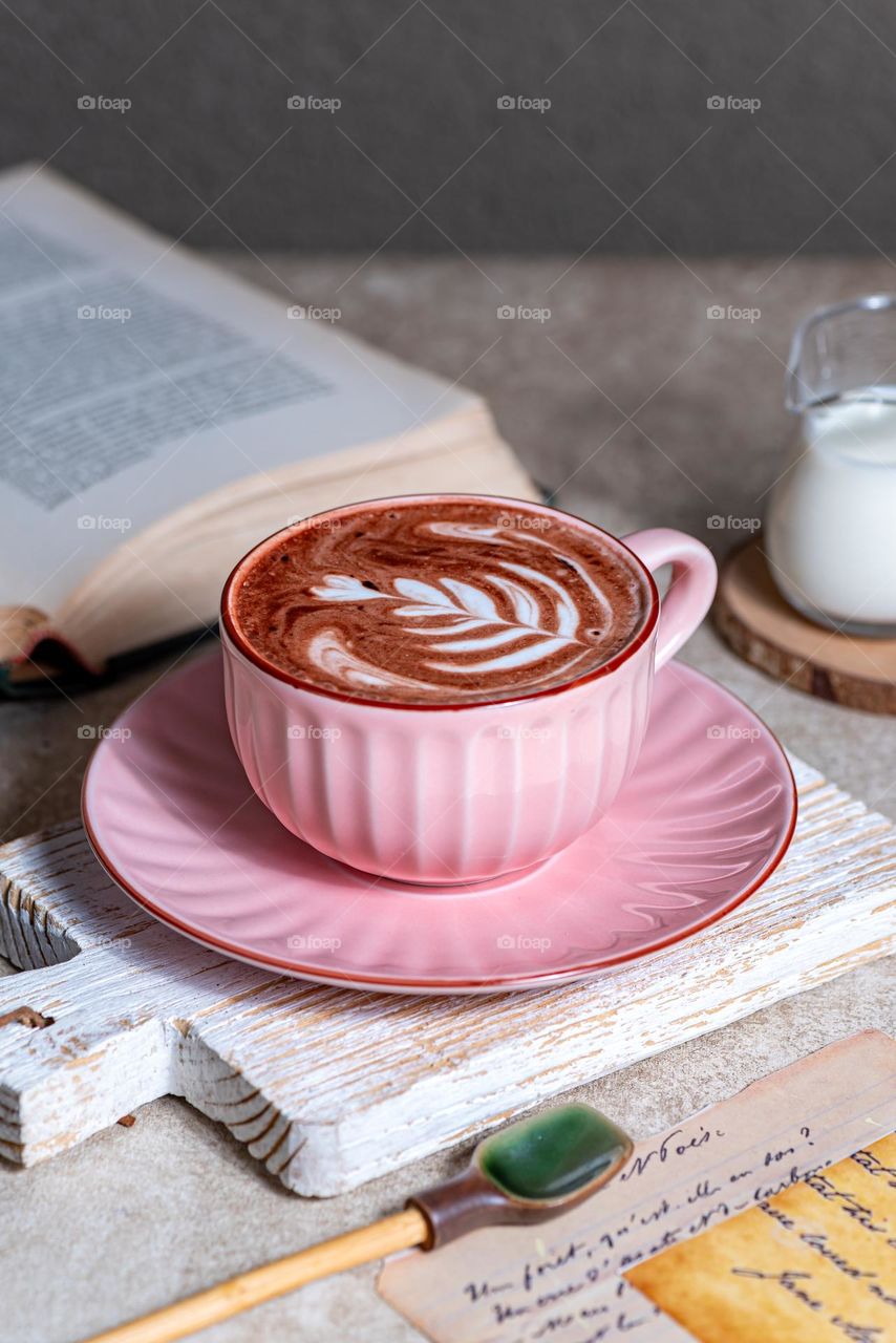 A fresh hot chocolate in a pink cup, served on the table