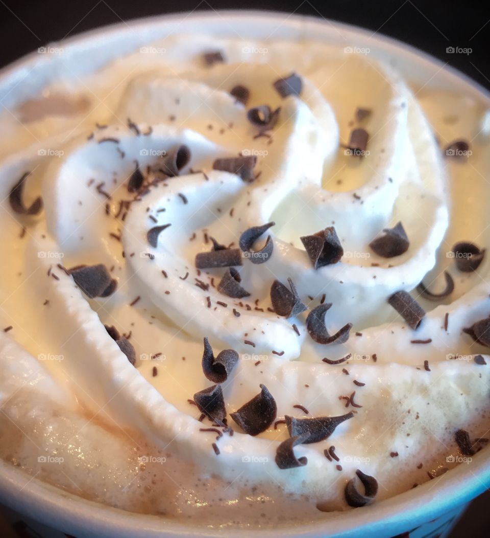 Closeup of the whipped cream topping on a coffee drink - chocolate shavings, foam and bits of cocoa 