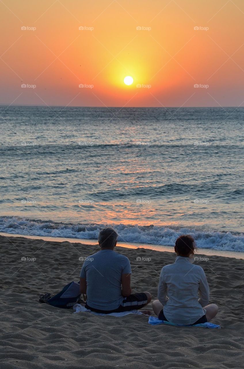 Couple Doing Yoga Outdoor at Sunrise on the Beach