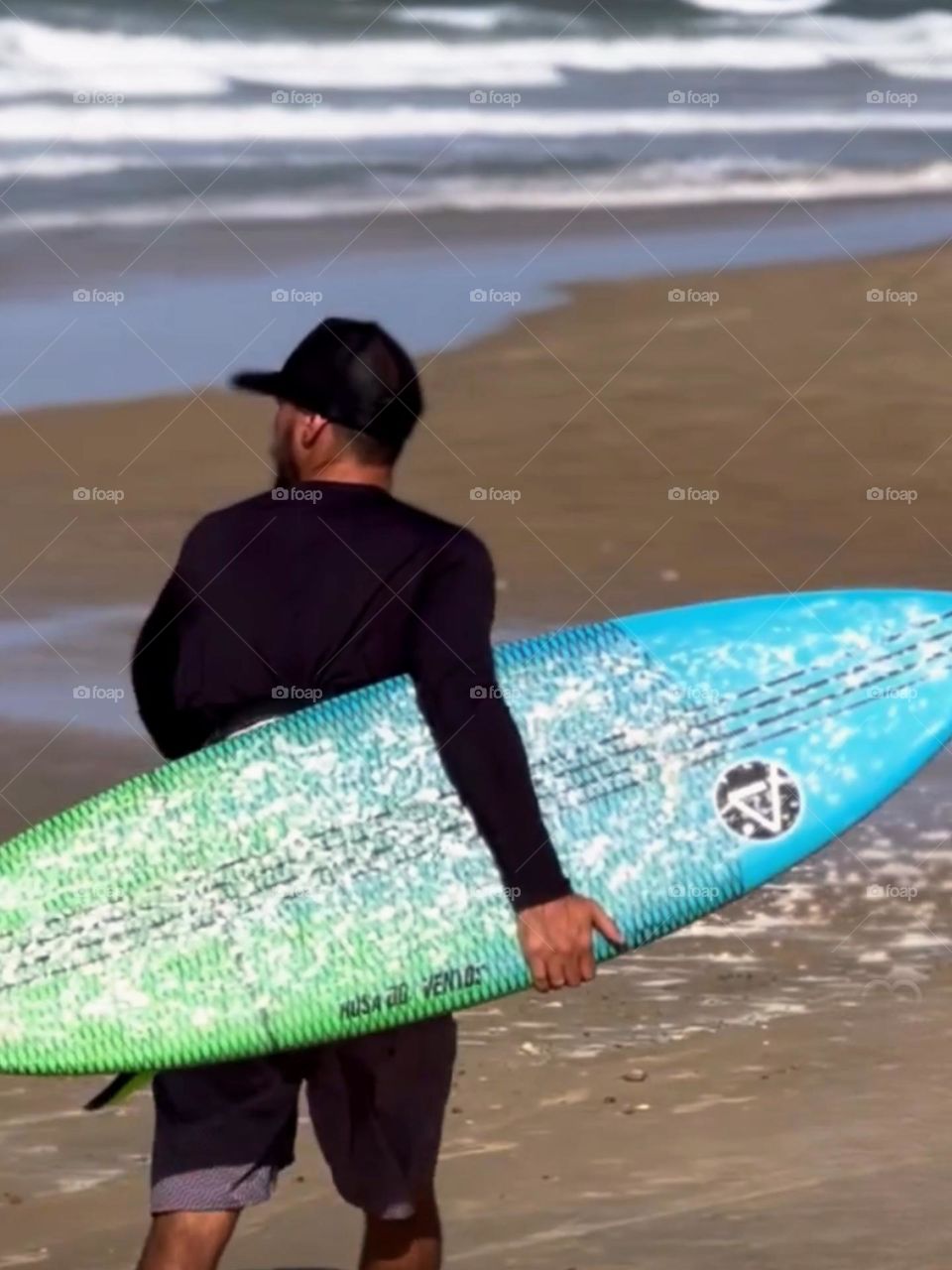 Surfer carrying his board on the beach