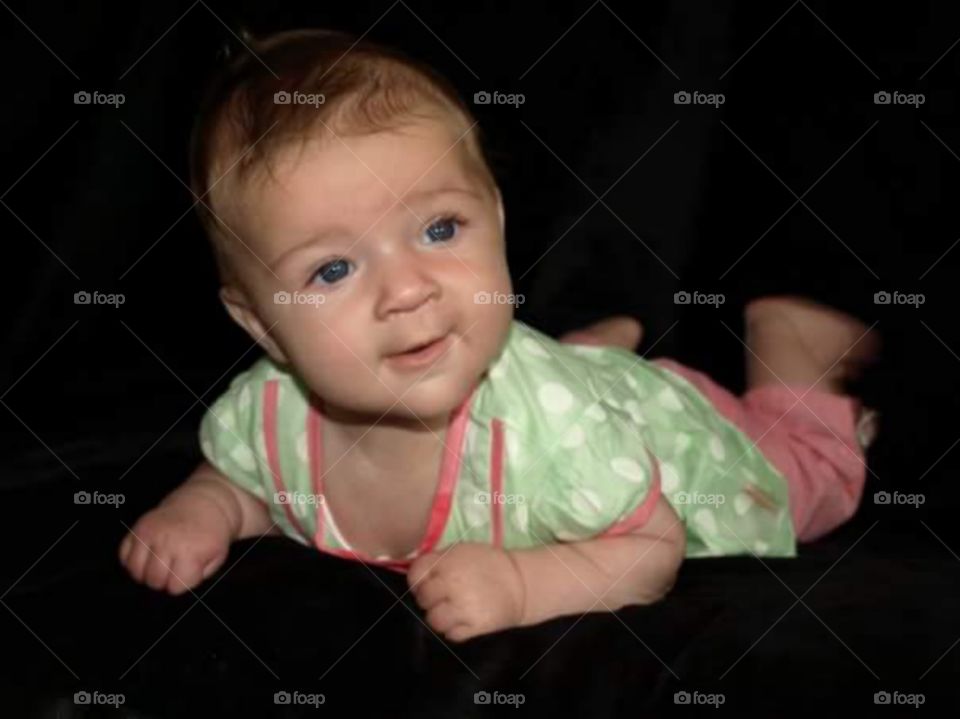 5 month old baby girl on her tummy . isolated on black.