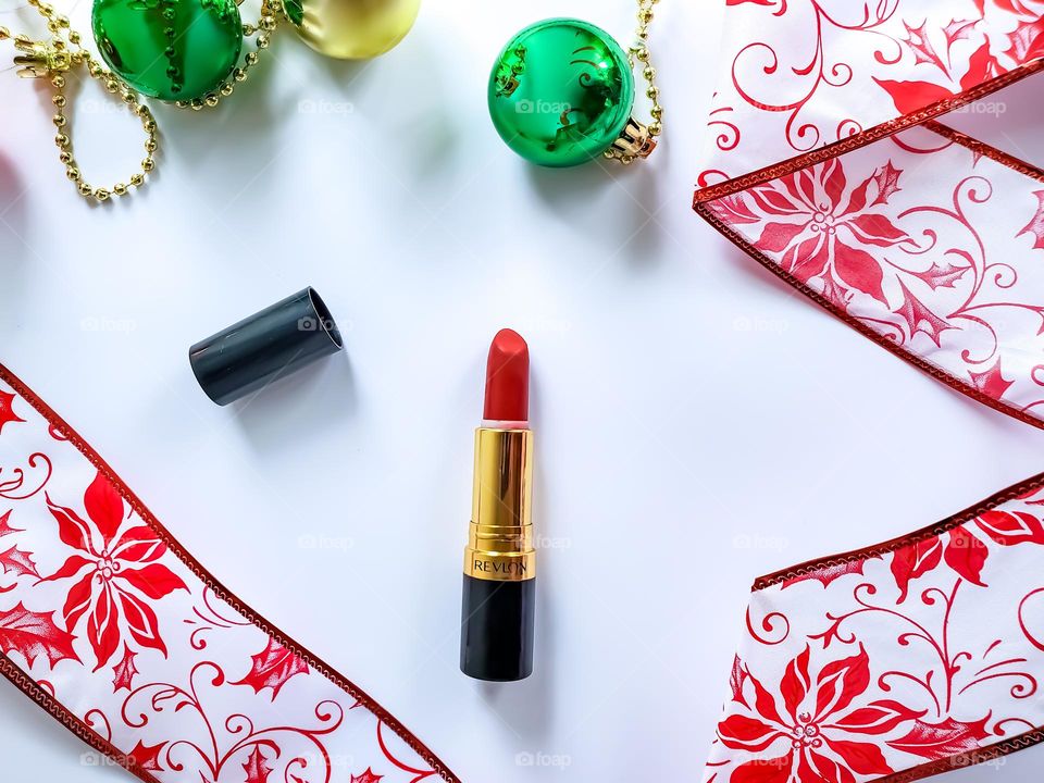 A vivacious red lipstick flatlay in a red, white and green holiday inspired theme.