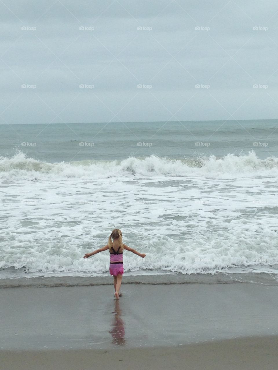 Little girl walking up to the ocean 