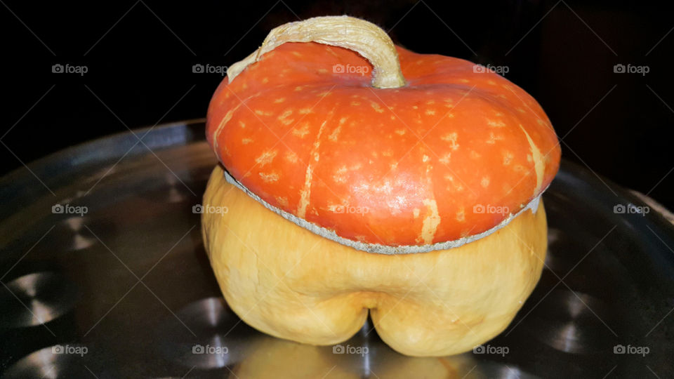 on a shiny iron tray placed a small yellow orange pumpkin, a unique colorful pumpkin, as if from a cartoon