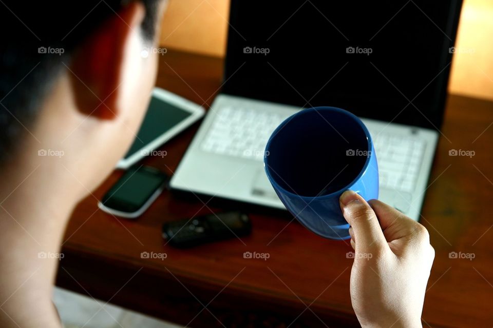 man drinking coffee while in front of computer