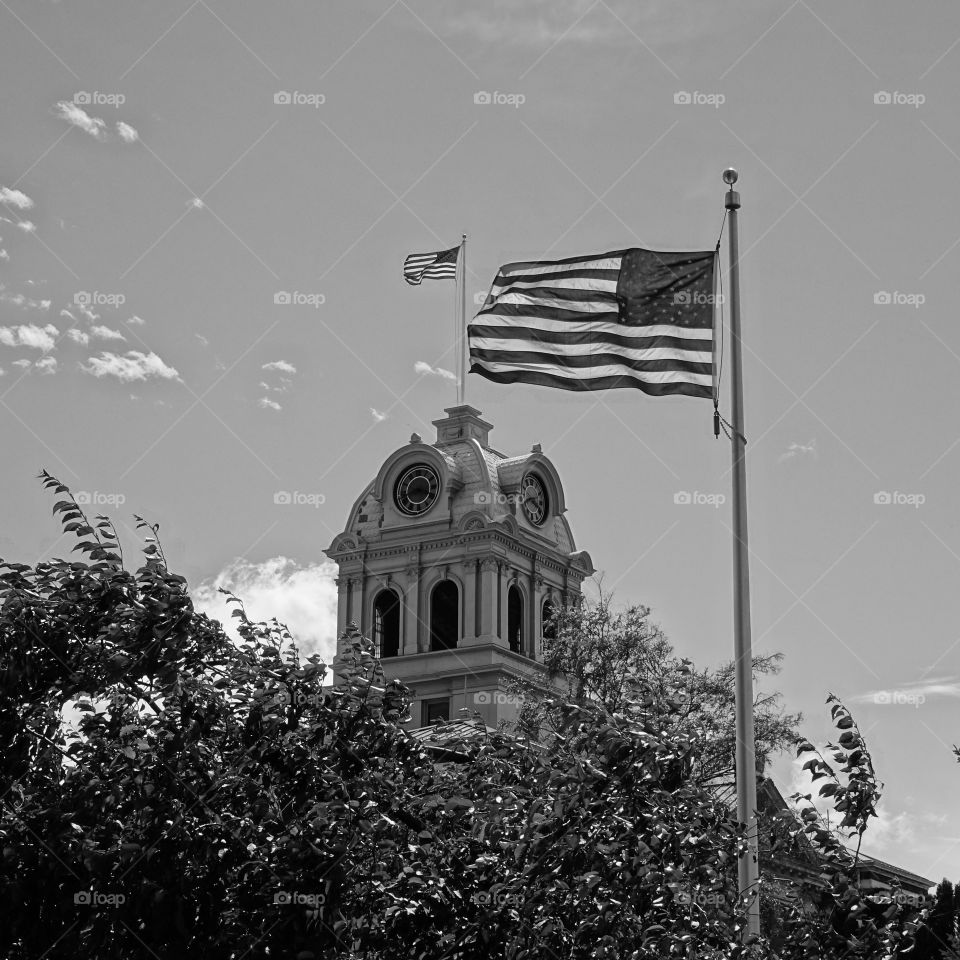 Double US flags at the Crook County Courthouse in Central Oregon in crisp black and white on a clear and sunny day. 