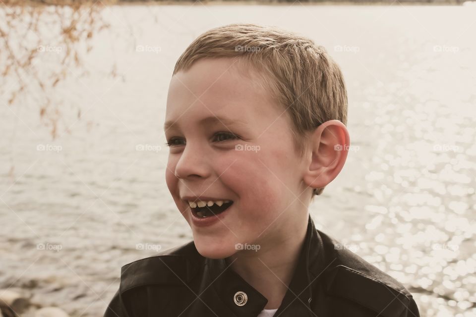 Happy boy smiling big at the lake in the Fall 