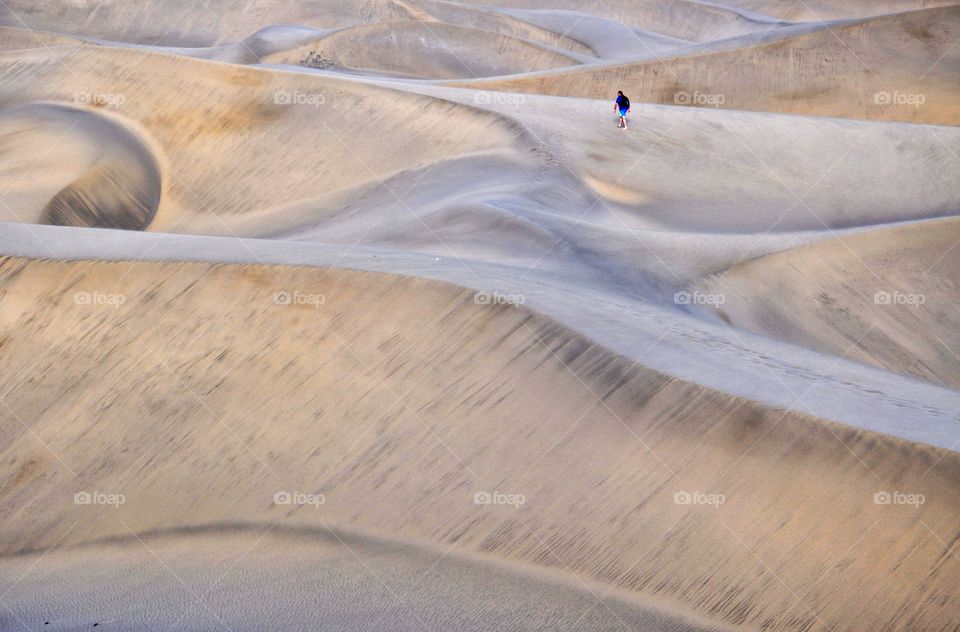 man walking in sandy dunes of maspalomas on gran canaria canary island in Spain