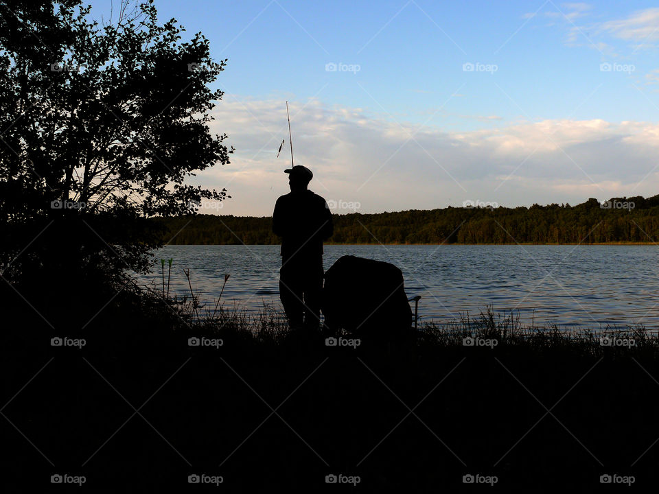 Silhouette of angler at lake in Kloster Lehnin, Germany.