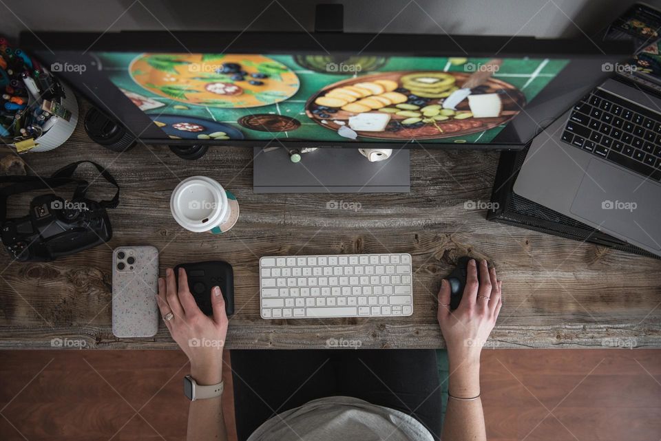 Person working at a computer desk from above 