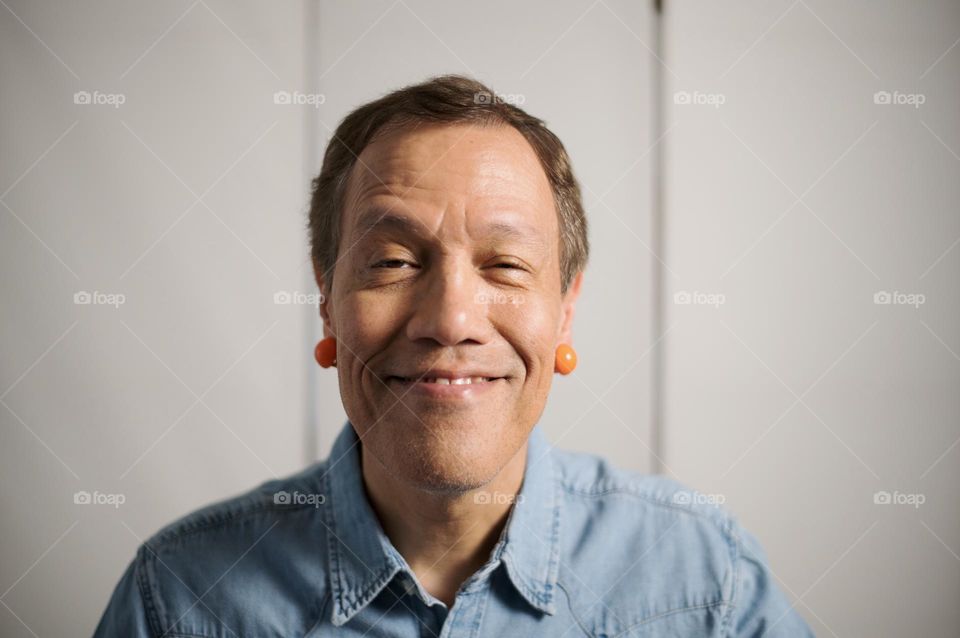 Portrait of a man wearing orange earrings 