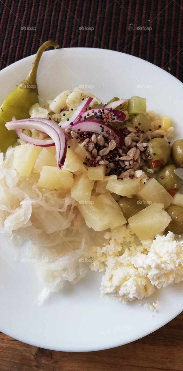 On the white plate pineapple, red onion, green olives, macaroni, seeds, cabbage, pepper, cottage cheese and pickled cucumber.
