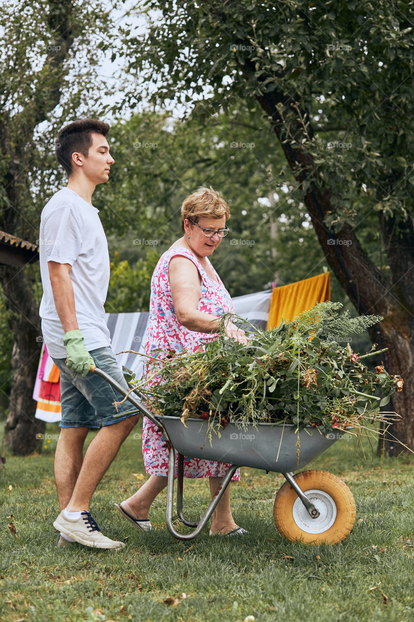 Grandchildren helping grandmother at a home garden. Candid people, real moments, authentic situations
