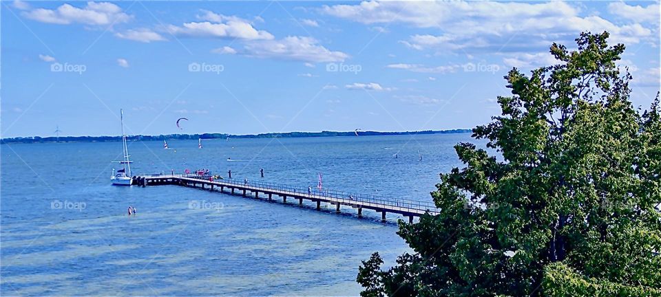 An old pier is still in use today at the “Strelasund”, part of the “Baltic Sea” on the island of “Rügen” in “Mecklenburg - Western Pomerania”, Germany. The sky is clear with just a few cumulus clouds in it. 2024. Hypnotic Productions