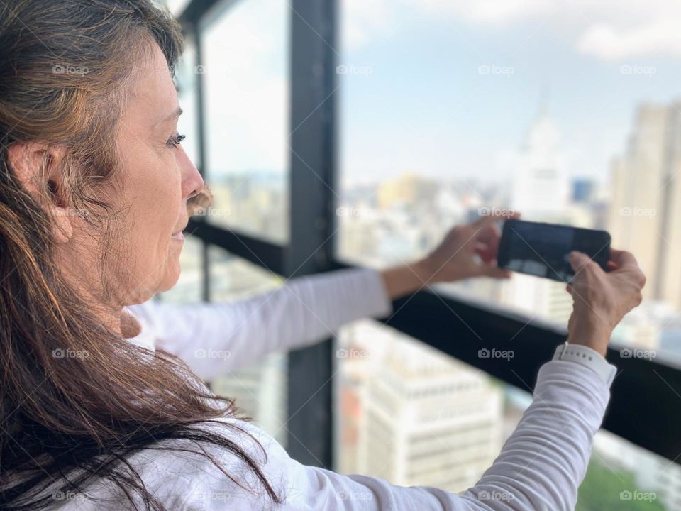 Millennial woman photographing the city from the top of a building