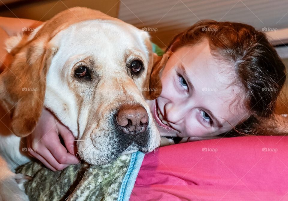 Child and her yellow Labrador retriever posing for a selfie 