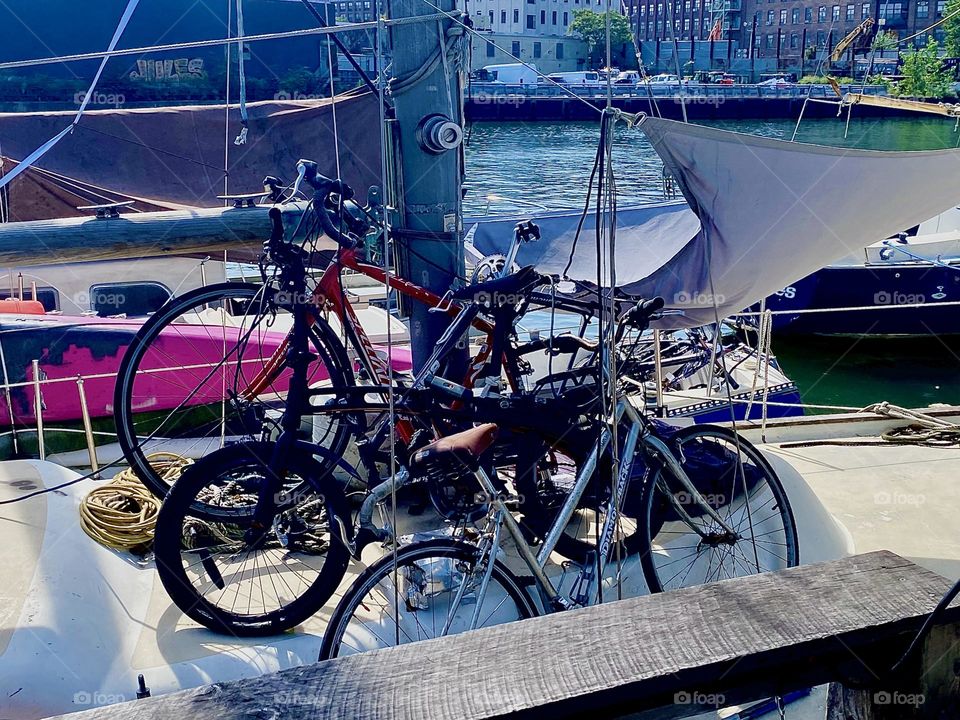 Three bicycles are tied to this boat at “Newtown Creek” by the “Pulaski Bridge” in LIC, Queens making it more difficult to get to which provides some degree of protection. 2023. Hypnotic Productions