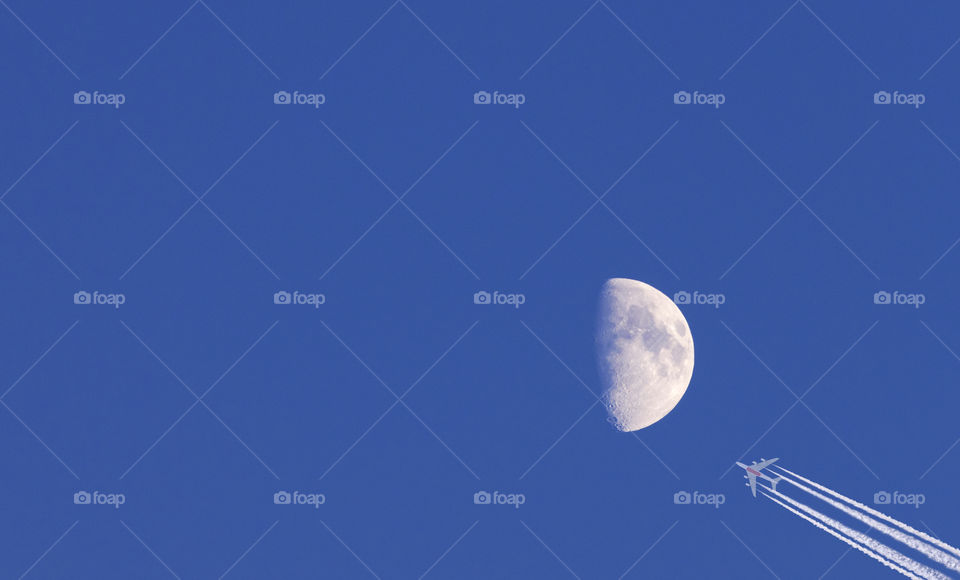 Moon and passenger airplane on blue sky background