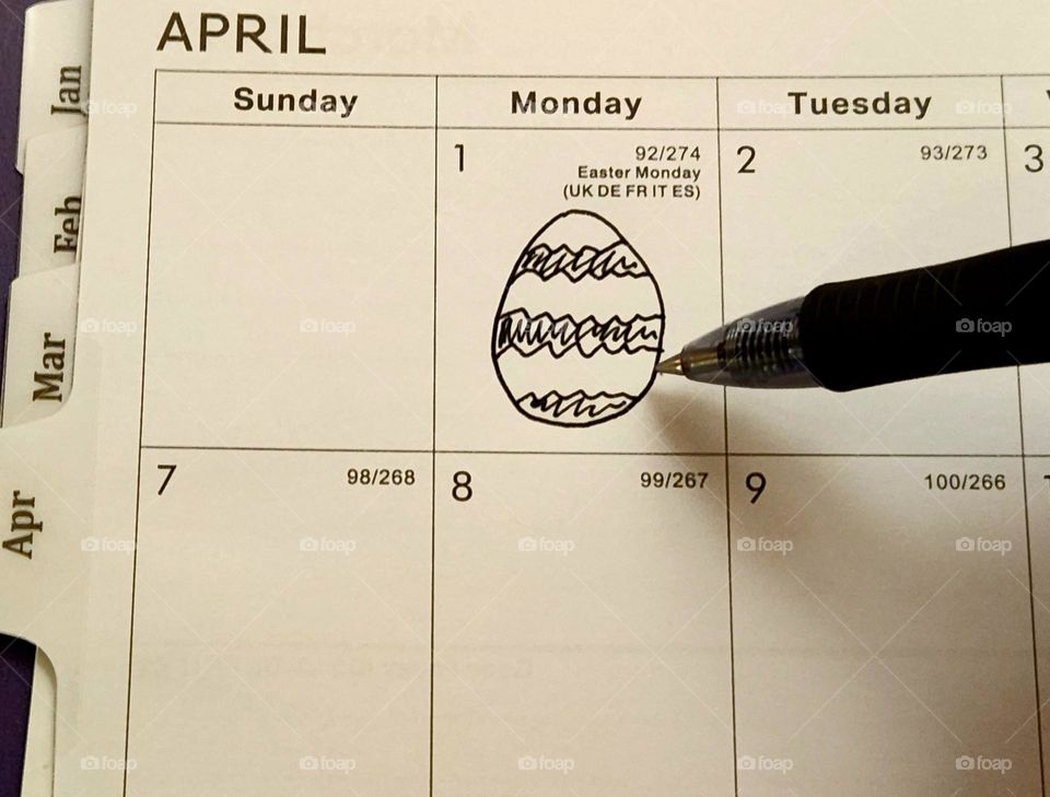 A pen drawing a decorated Easter egg in a planner book page for the month of April